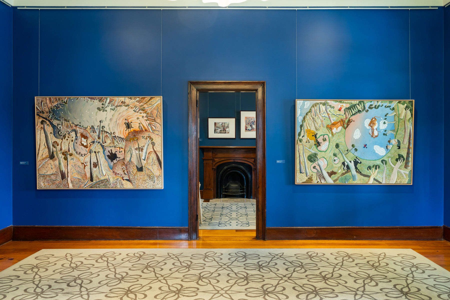 Two William Robinson paintings hanging either side of a doorway in the William Robinson Gallery